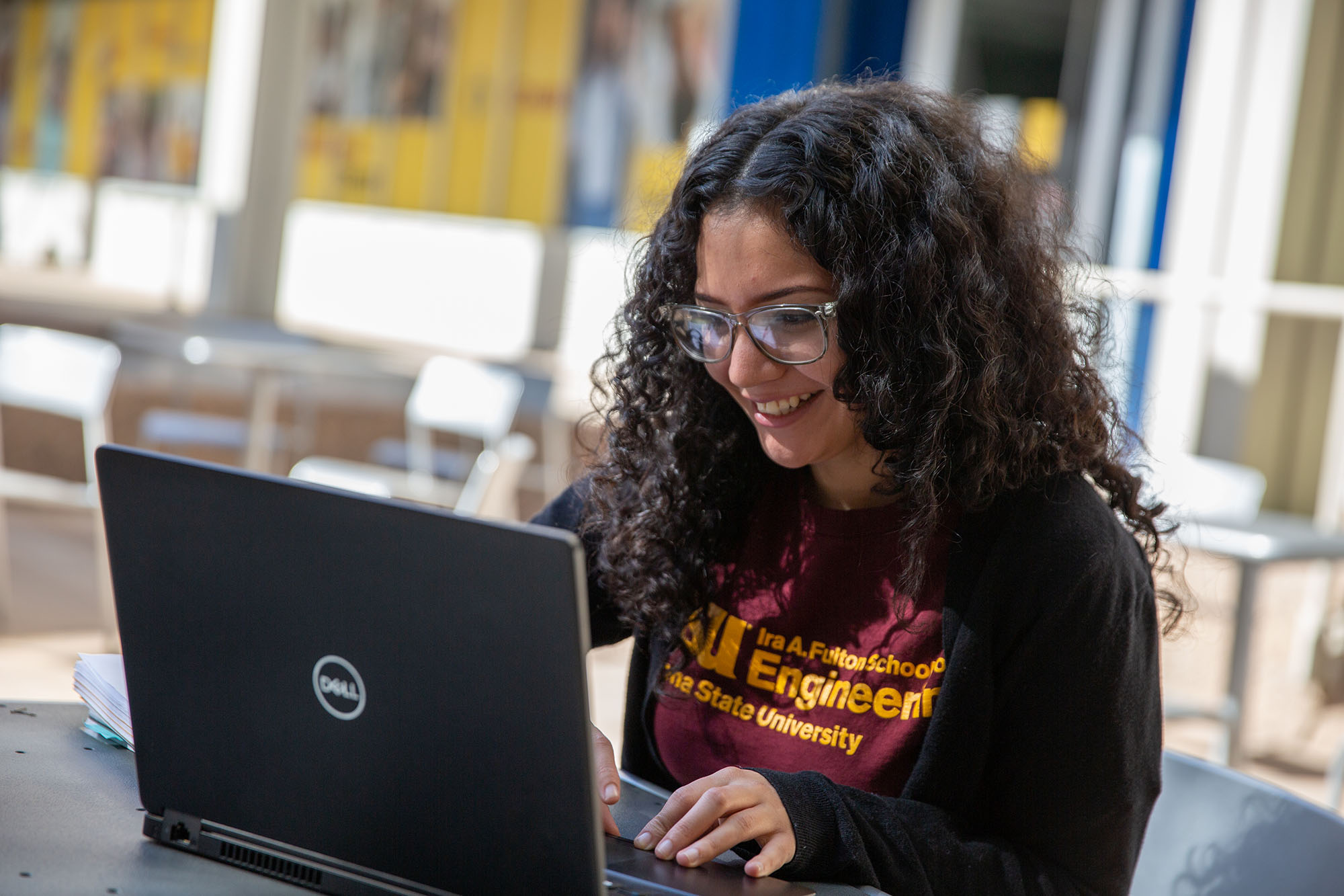 Students sits in front of a laptop smiling.