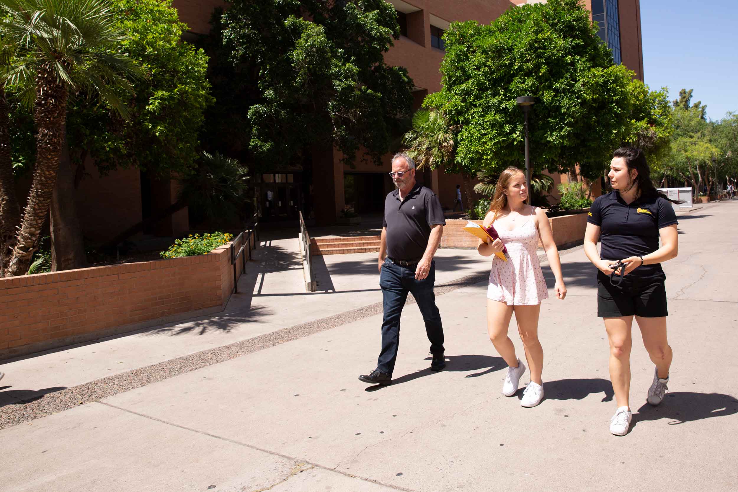 A Fulton Ambassador gives a tour to a prospective student and her father. They walk along Palm Walk on the Tempe campus