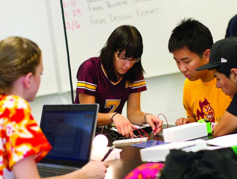 A group of students in a classroom puts together an electrical device